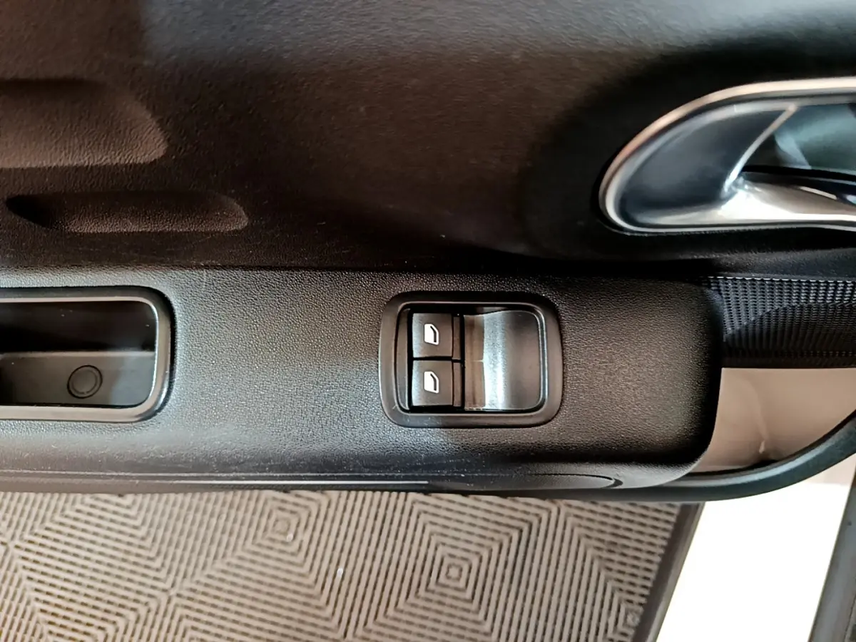 Gros plan sur les commandes électriques des vitres côté conducteur d'une Citroën C3 blanche de 2018.
