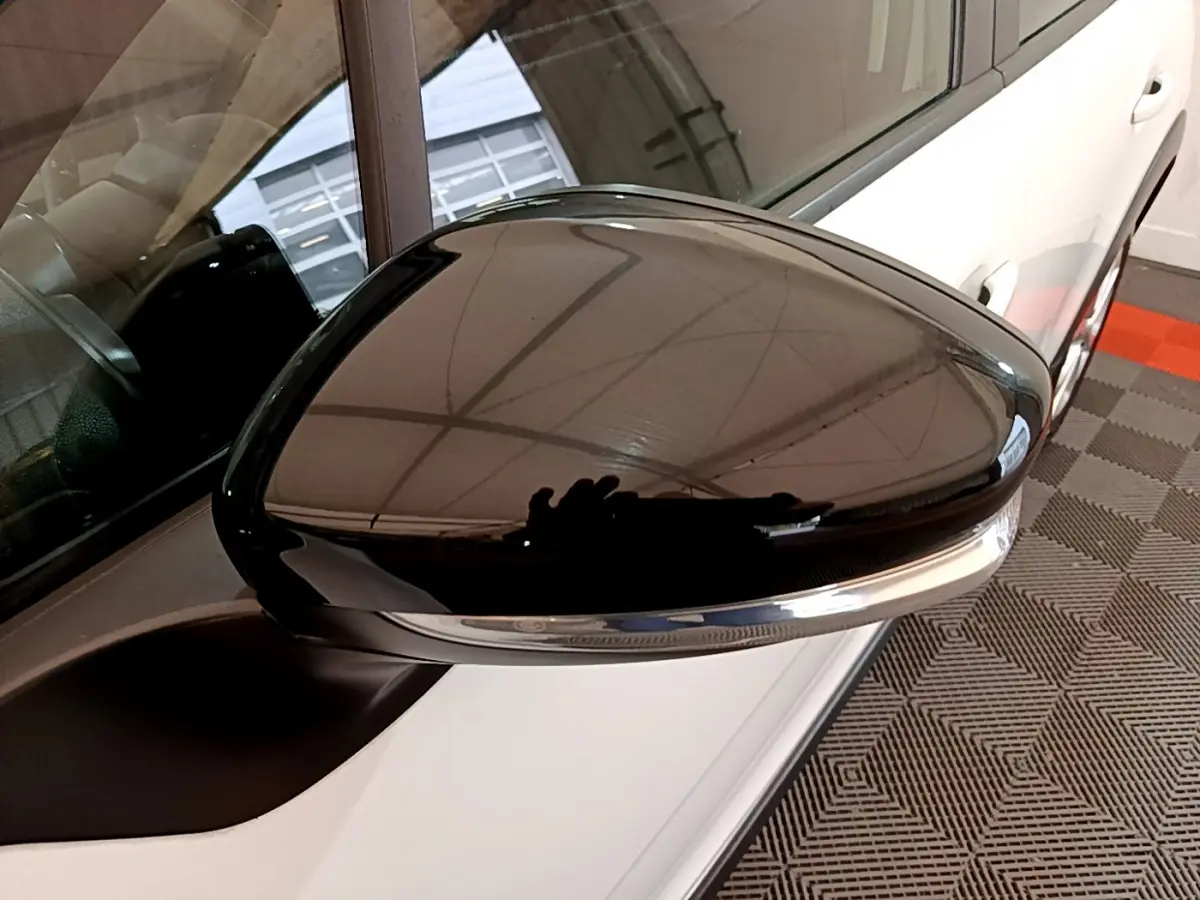 Rétroviseur droit noir brillant sur une Citroën C3 blanche vue de près côté conducteur.