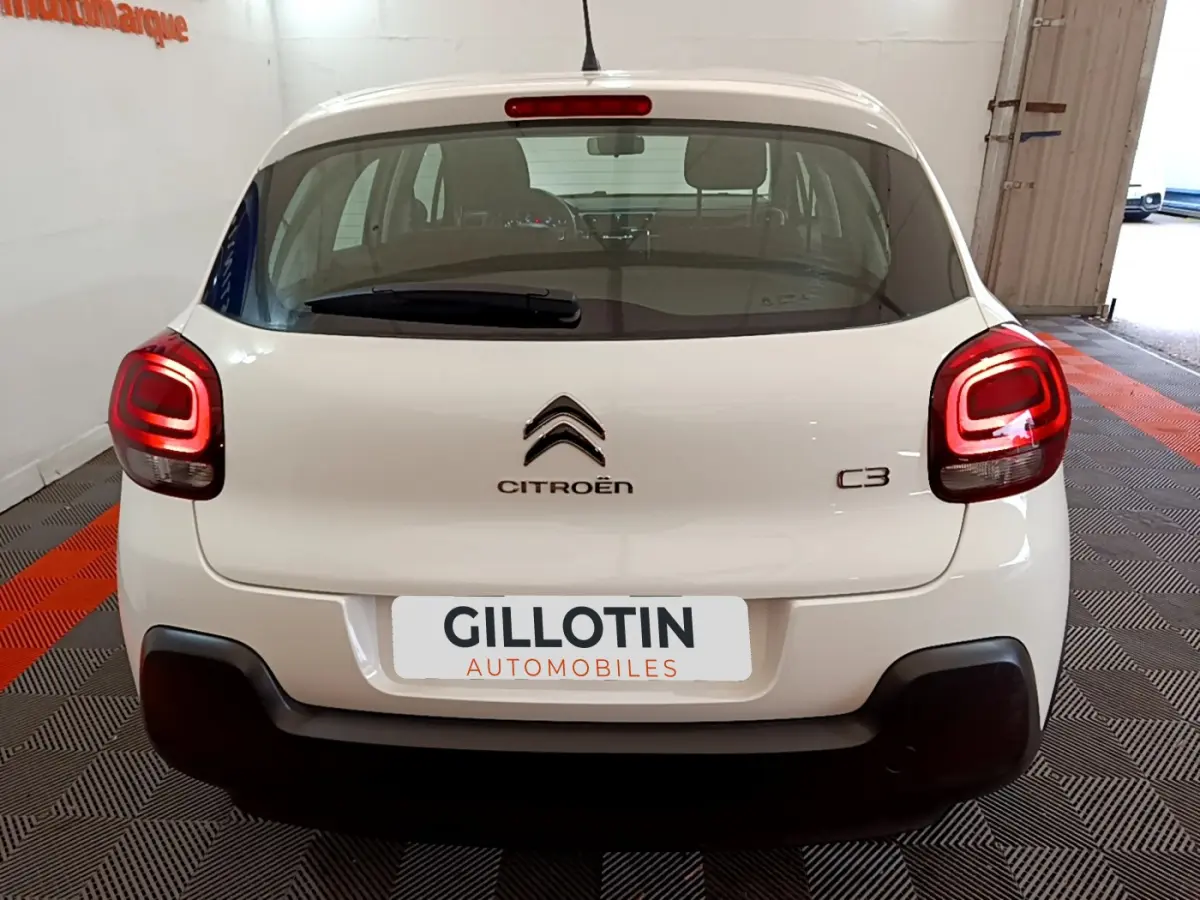 Vue arrière d'une Citroën C3 blanche de 2018 avec feux arrière allumés dans un showroom.