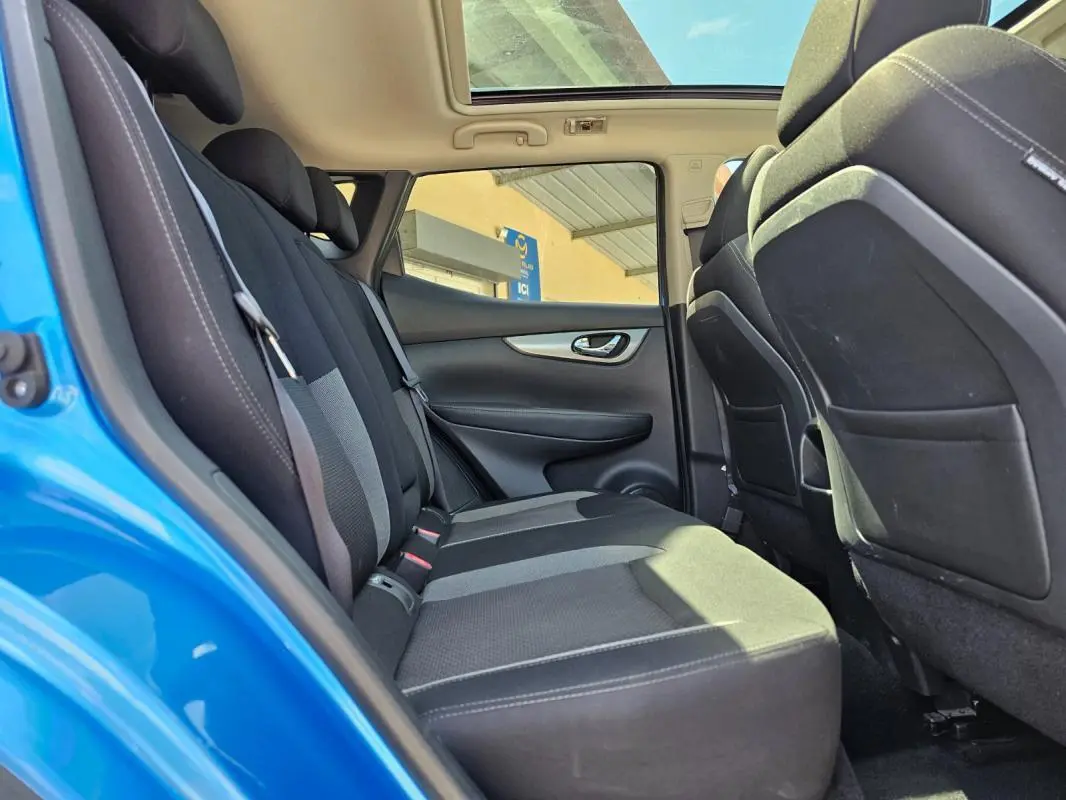 Vue intérieure arrière côté gauche du Nissan Qashqai bleu 2019, montrant les sièges arrière et le toit ouvrant panoramique.