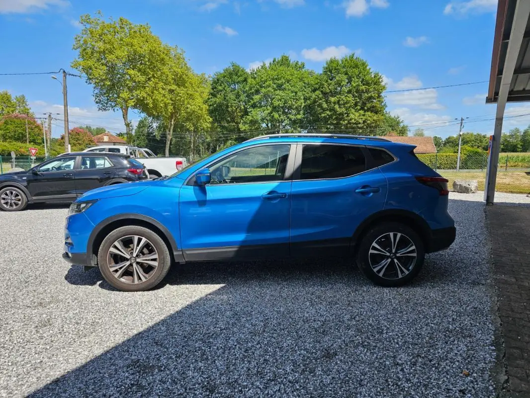Vue de profil côté gauche d'un Nissan Qashqai bleu 2019 avec jantes alliage et toit noir partiel.