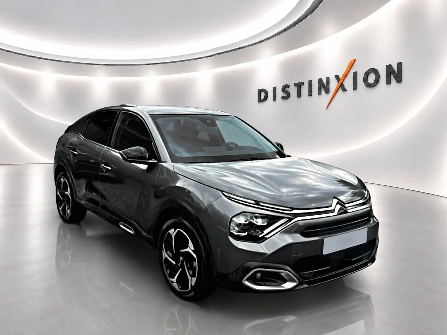 Citroën C4 gris 3/4 avant droit dans showroom avec jantes alu et vitres teintées.