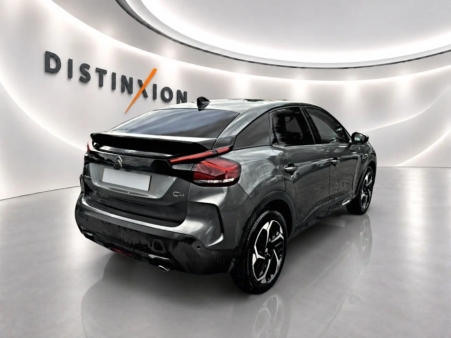 Vue 3/4 arrière droite d'une Citroën C4 gris métallisé avec jantes alliage et vitres surteintées en showroom.