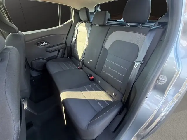 Vue intérieure côté droit de la banquette arrière noire du Dacia Sandero Stepway gris foncé avec ceinture de sécurité et appuie-têtes.
