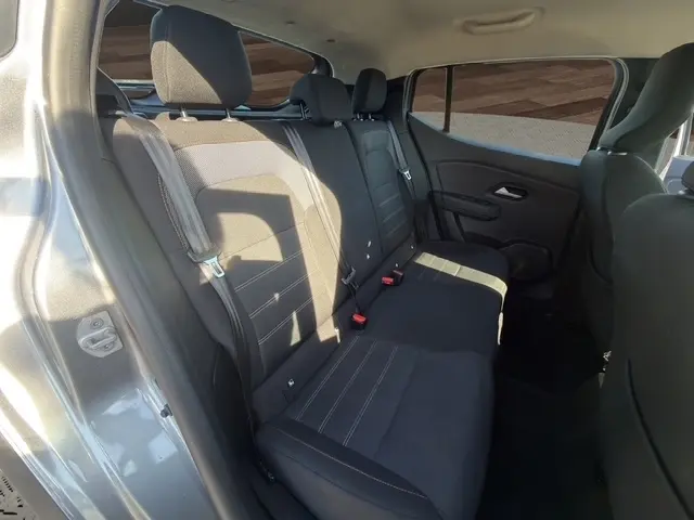 Vue intérieure côté gauche des sièges arrière noirs d’une Dacia Sandero Stepway gris foncé avec ceintures et appuie-têtes visibles.