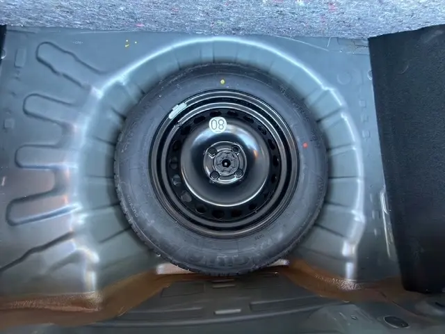 Roue de secours noire montée dans le coffre d'une Dacia Sandero Stepway gris foncé, vue de dessus.