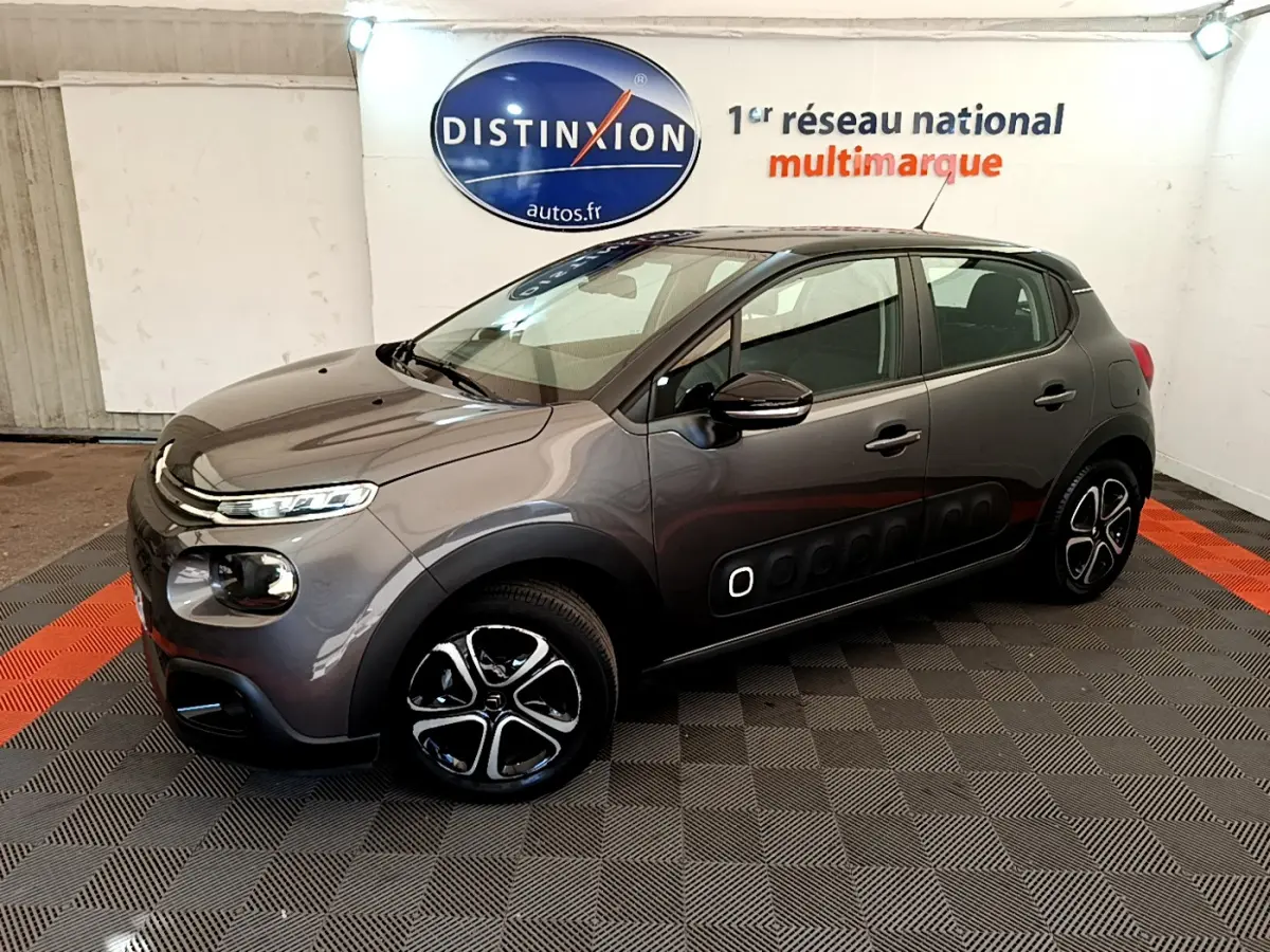 Citroën C3 gris foncé vue 3/4 avant droit, avec protections latérales noires et jantes stylisées en concession.
