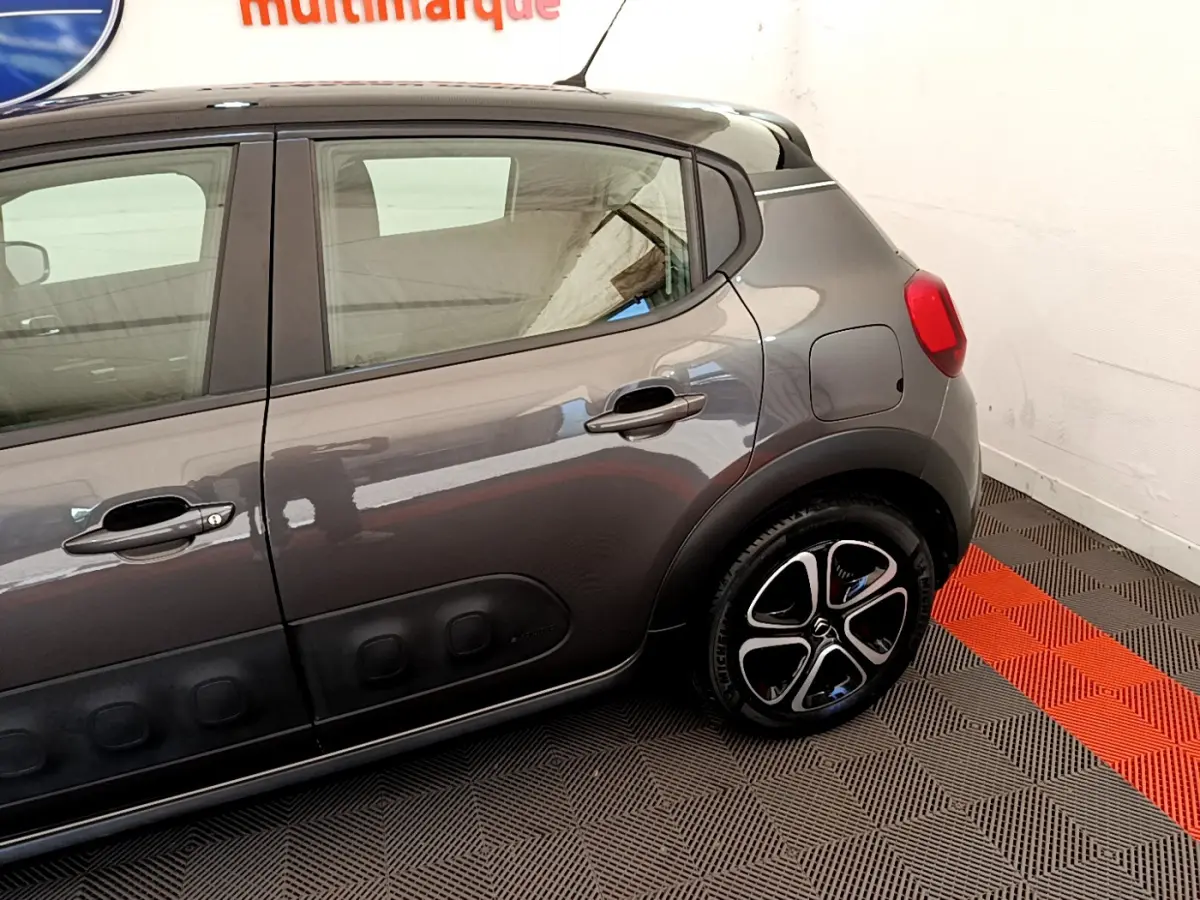 Vue latérale droite d'une Citroën C3 gris foncé avec protections de porte noires et jantes distinctives.