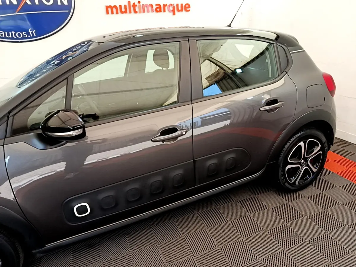 Profil côté gauche d'une Citroën C3 gris foncé avec protections latérales noires et jantes distinctives.