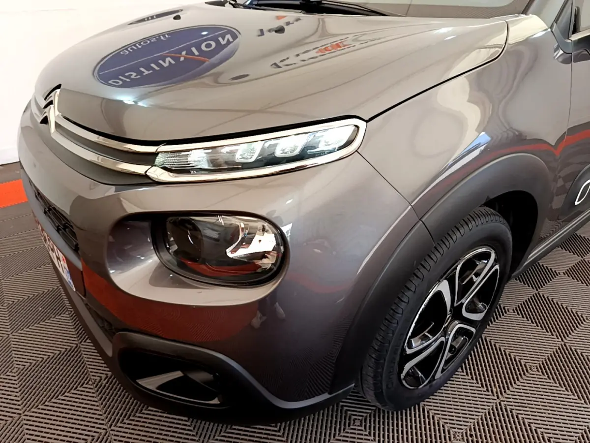 Vue 3/4 avant droit d'une Citroën C3 gris foncé avec phares LED et jantes alliage distinctives.