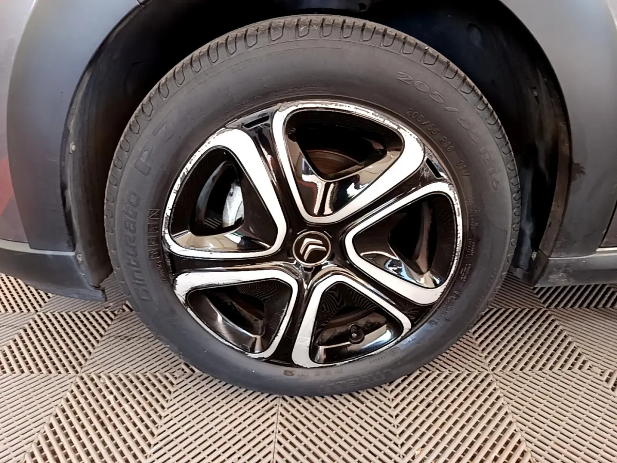 Gros plan sur la jante noire et chromée d'une Citroën C3 gris foncé, roue avant droite visible.