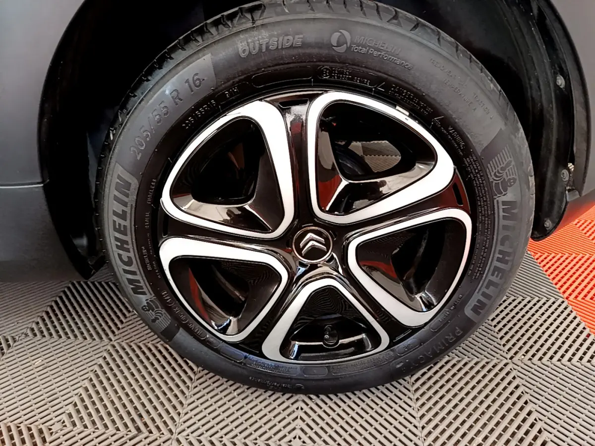 Gros plan sur la roue avant droite d'une Citroën C3 gris foncé, jante alliage noire et argentée avec logo Citroën central.