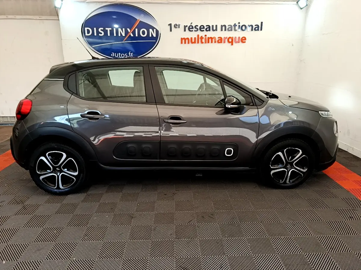 Profil côté gauche d'une Citroën C3 gris foncé 2019 avec protections latérales noires caractéristiques et jantes stylisées.