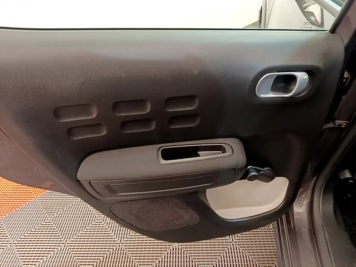 Vue rapprochée de la porte côté gauche gris foncé de la Citroën C3 2019 avec poignée intérieure et manivelle de vitre.