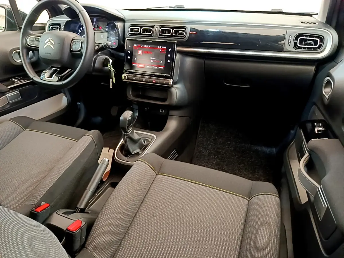 Vue intérieure avant de la Citroën C3 PureTech 82 Shine 2019, tableau de bord noir avec écran tactile central et volant cuir.