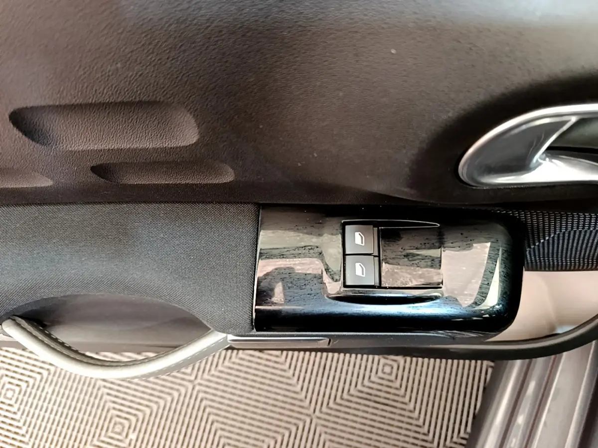 Gros plan sur les commandes des vitres électriques côté conducteur d'une Citroën C3 gris foncé 2019.