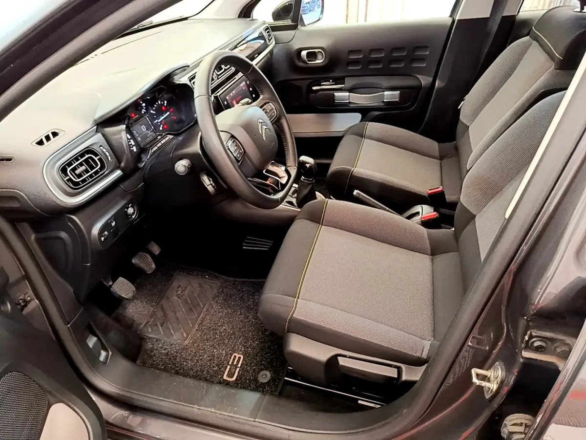 Intérieur avant droit de la Citroën C3 gris foncé 2019, avec tableau de bord tactile et sièges tissu gris.