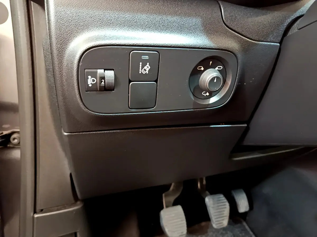 Détail du tableau de bord côté gauche avec commandes de réglage des phares et rétroviseurs sur Citroën C3 gris foncé 2019.