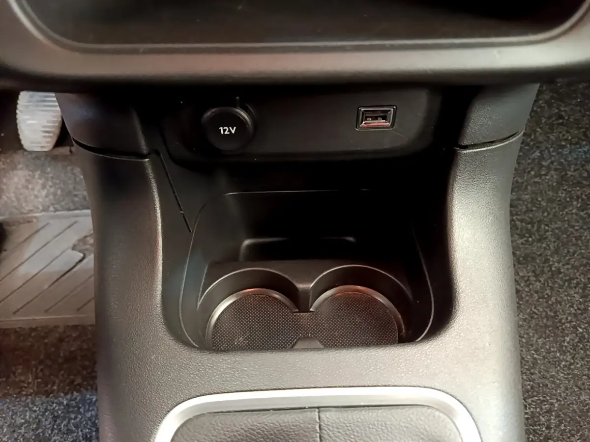 Gros plan sur la console centrale noire de la Citroën C3 2019 avec prise 12V, port USB et porte-gobelets.