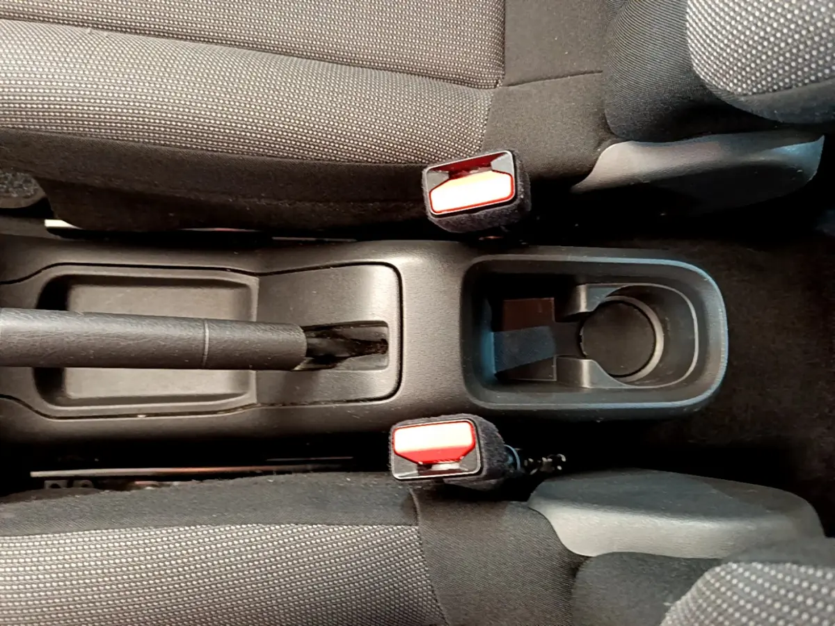 Vue rapprochée de la console centrale avec frein à main et porte-gobelet entre les sièges avant gris foncé d'une Citroën C3.