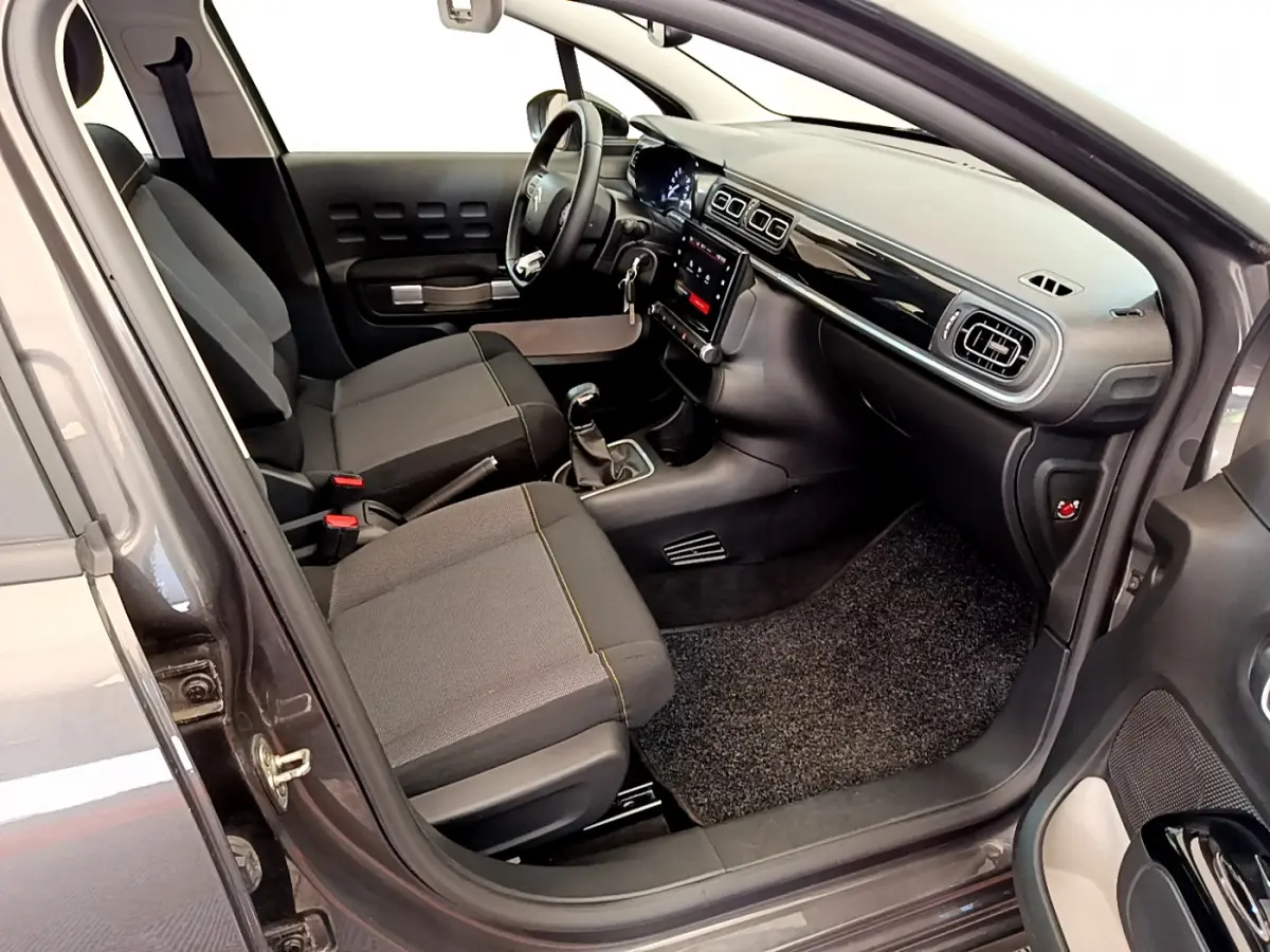 Intérieur avant droit de la Citroën C3 gris foncé 2019, avec tableau de bord noir brillant et écran tactile central.