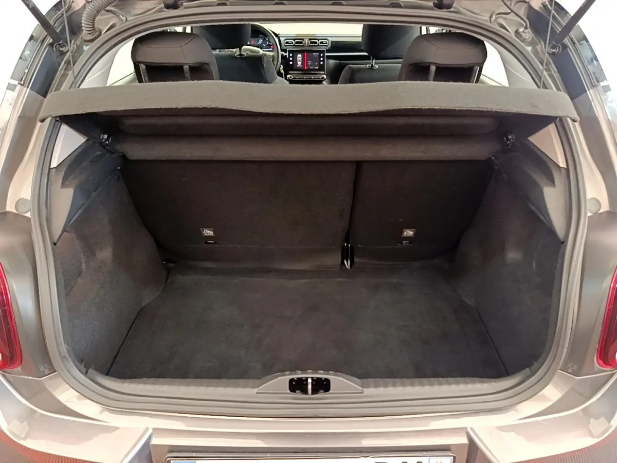 Coffre ouvert d'une Citroën C3 gris foncé vue arrière, banquette arrière et tableau de bord visibles à l'intérieur.