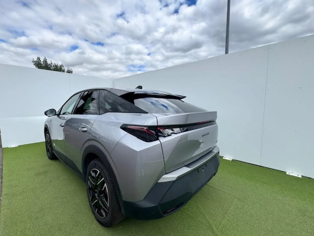 Vue 3/4 arrière gauche du Peugeot 3008 gris Artense avec toit noir, feux arrière à griffes LED et jantes alliage noires.