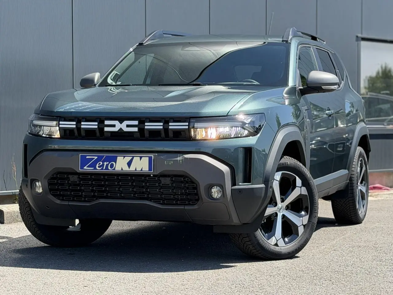 Vue 3/4 avant d'un Dacia Duster Hybrid-G 150 4X4 Journey vert cèdre avec jantes alliage et signature lumineuse LED.