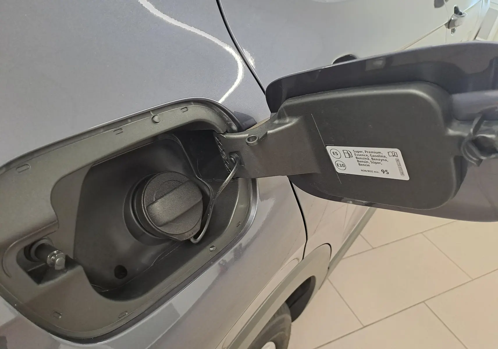 Gros plan sur la trappe à carburant ouverte côté gauche d’un Volkswagen T-Cross gris cendré métallisé 2025.
