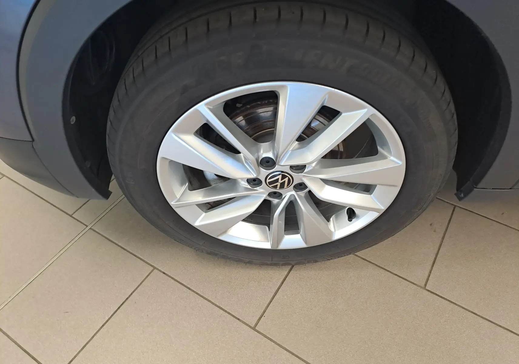 Gros plan sur la jante alliage argentée d’un Volkswagen T-Cross gris cendré, vue côté roue avant.