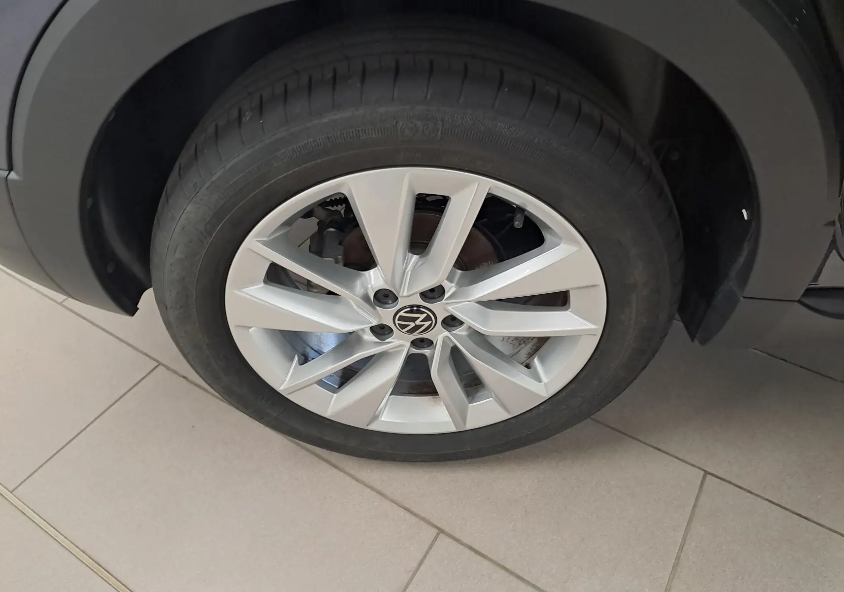 Gros plan sur la roue avant droite du Volkswagen T-Cross gris cendré avec jante alliage à 5 doubles branches.