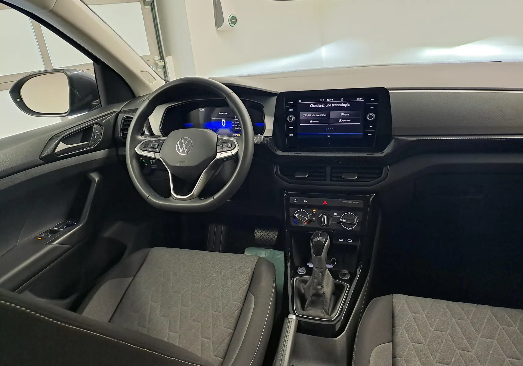 Vue intérieure avant du Volkswagen T-Cross 2025, tableau de bord moderne avec écran tactile et volant multifonction noir.