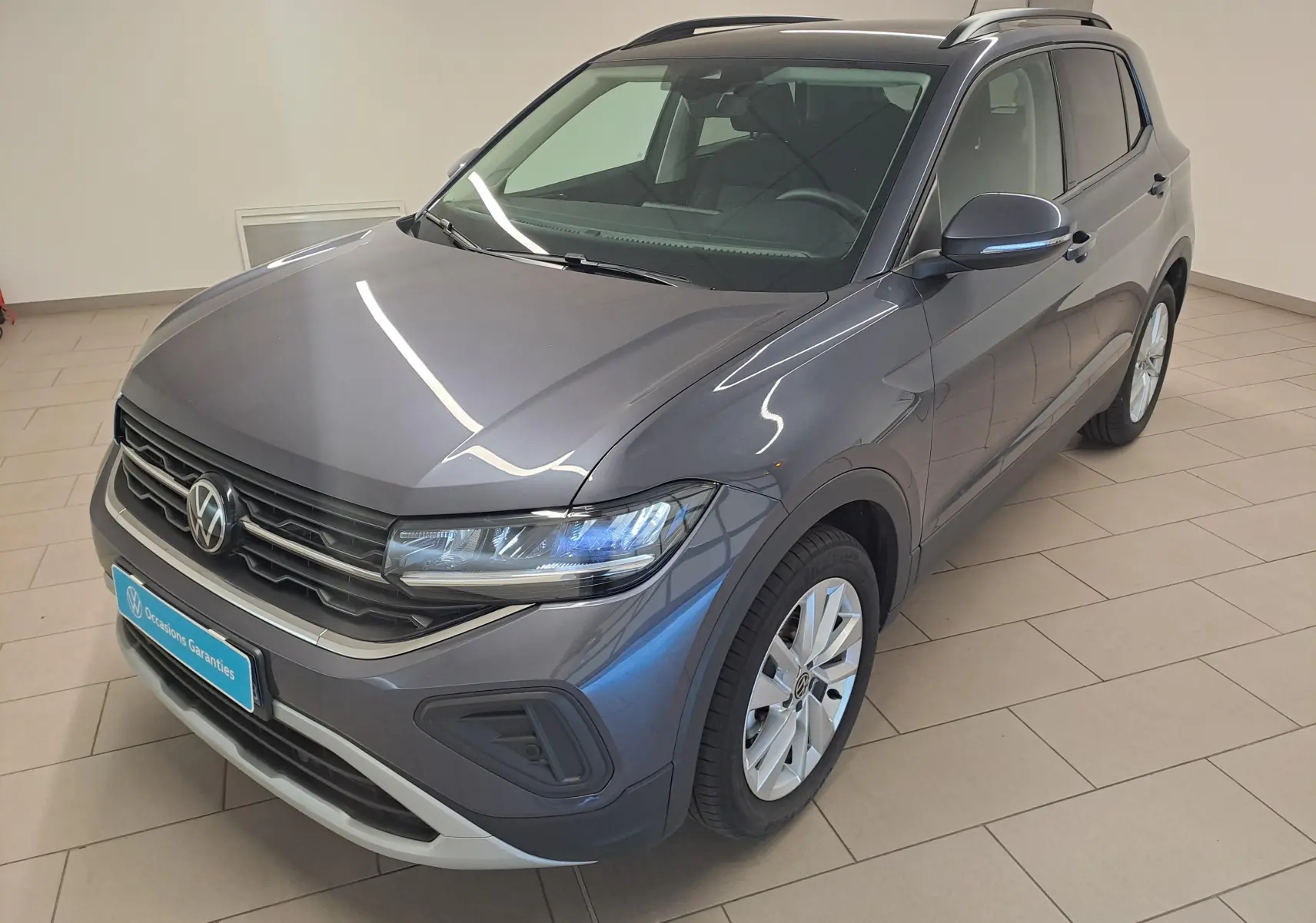 Volkswagen T-Cross gris cendré en vue 3/4 avant droit, avec calandre noire et jantes alliage argentées.