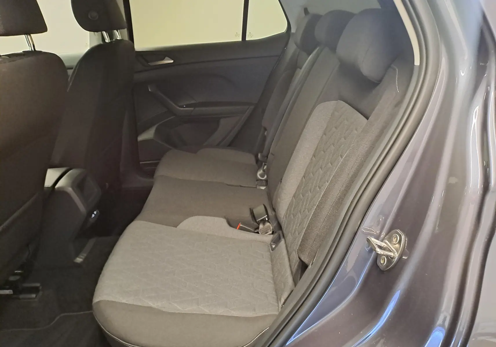 Vue intérieure côté droit des sièges arrière gris tissu du Volkswagen T-Cross 2025 Gris Cendré avec porte ouverte.