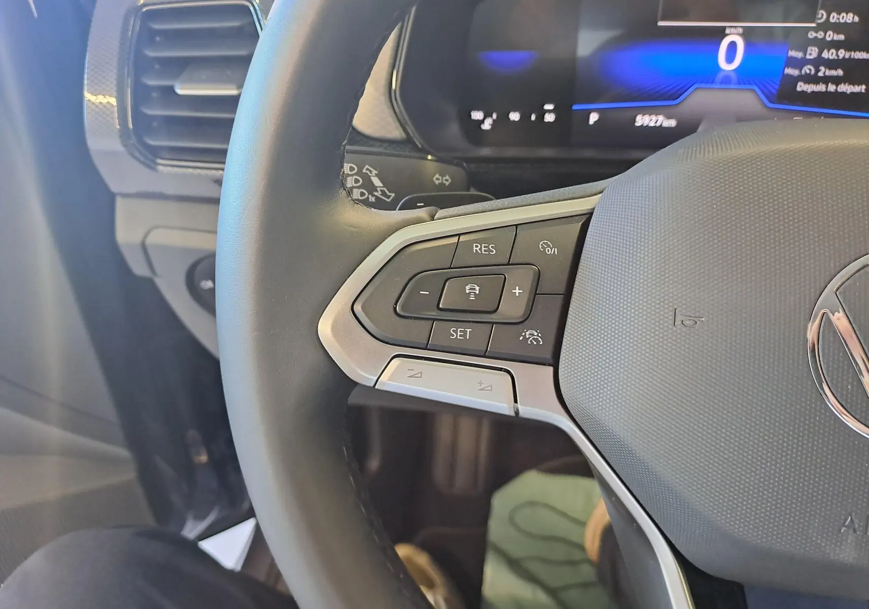 Gros plan sur le volant côté gauche du Volkswagen T-Cross 2025 avec commandes de régulateur et tableau de bord numérique.