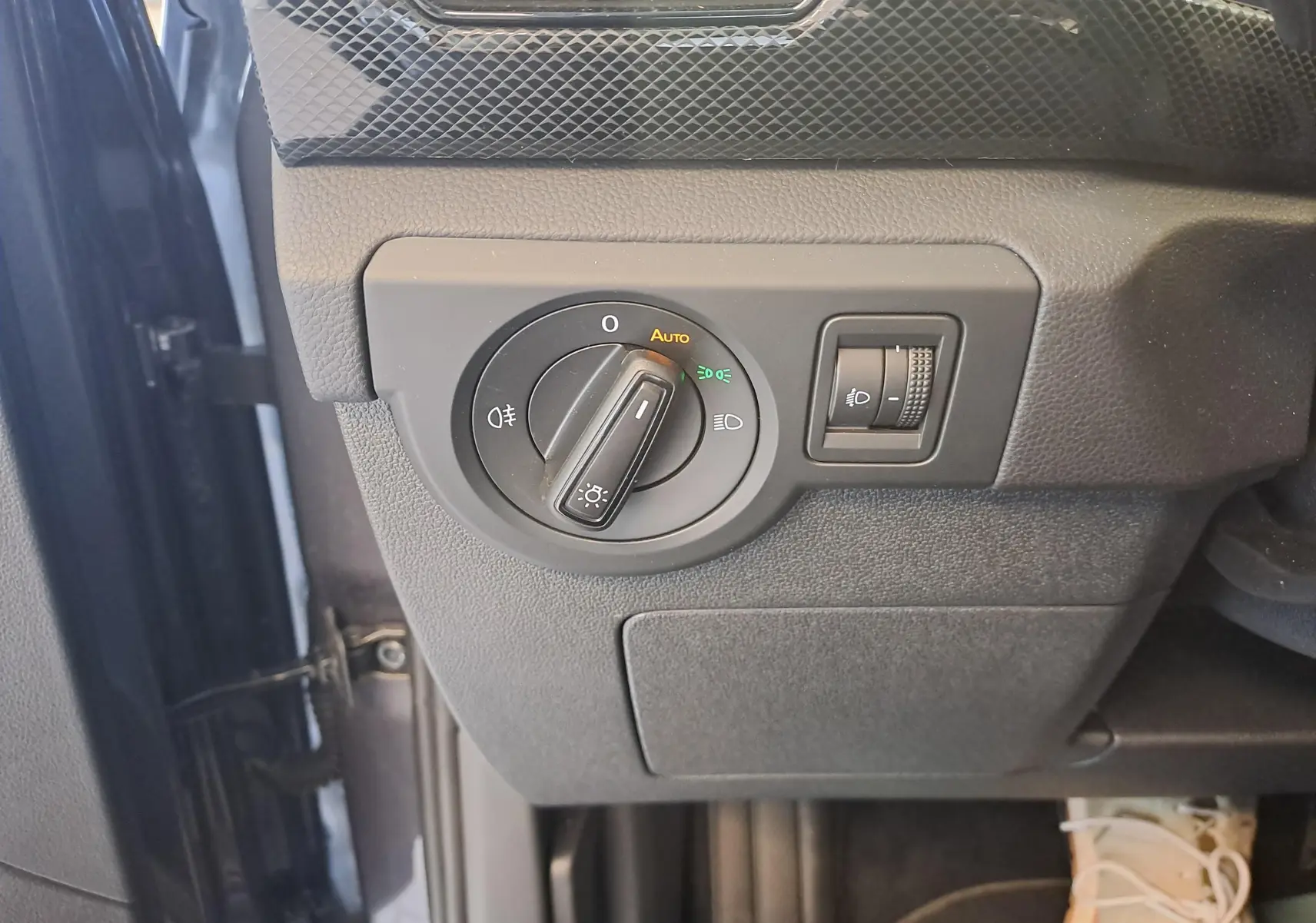 Vue rapprochée du bouton de commande des phares sur le côté gauche du tableau de bord du Volkswagen T-Cross gris cendré 2025.