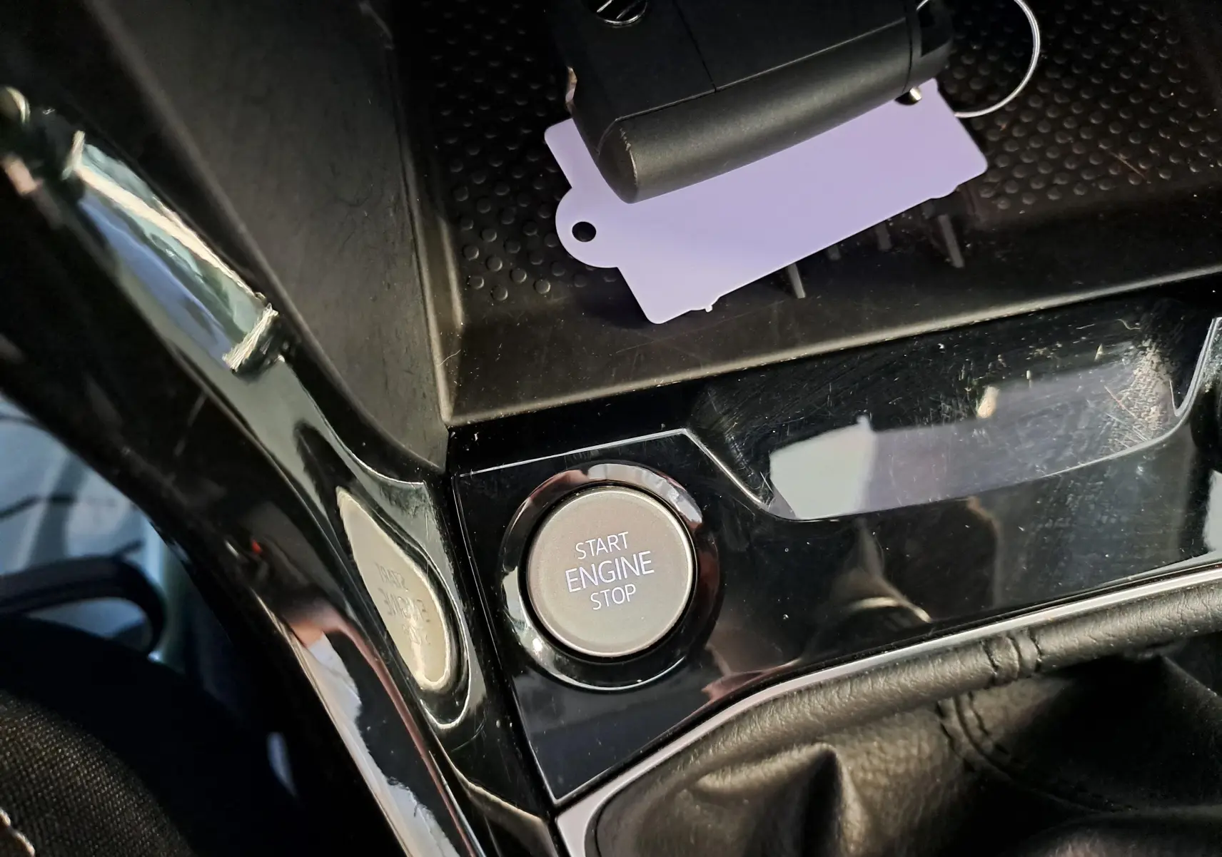 Gros plan sur le bouton Start Engine Stop et clé VW dans la console centrale noire brillante du Volkswagen T-Cross Gris Cendré.