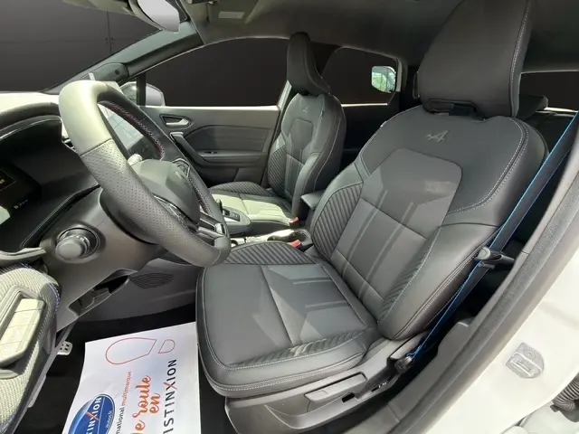 Vue intérieure côté conducteur du Renault Captur Esprit Alpine hybride, sièges noirs avec logo Alpine brodé sur l'appui-tête.