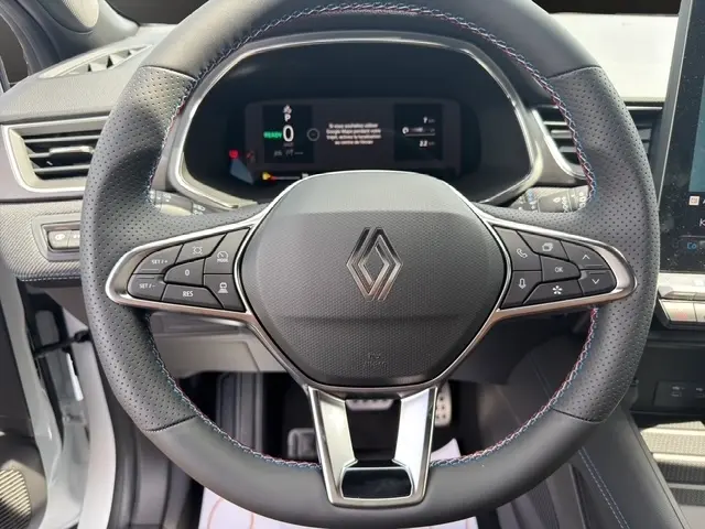 Vue rapprochée du volant en cuir noir perforé du Renault Captur 2026 avec commandes multifonctions et logo central.