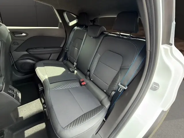 Vue intérieure arrière droite du Renault Captur blanc, sièges noirs avec surpiqûres bleues et banquette 3 places.