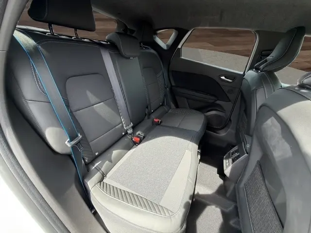 Vue intérieure arrière droite du Renault Captur blanc esprit Alpine, sièges noirs avec surpiqûres bleues et ceintures grises.