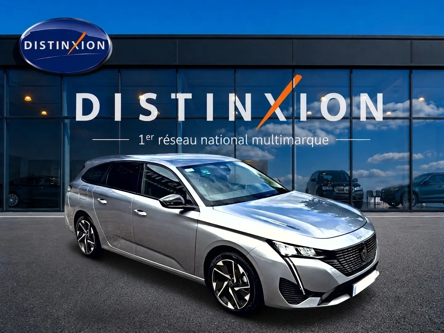 Peugeot 308 SW gris vue 3/4 avant droit, jantes alliage et vitres arrière surteintées devant showroom Distinxion.