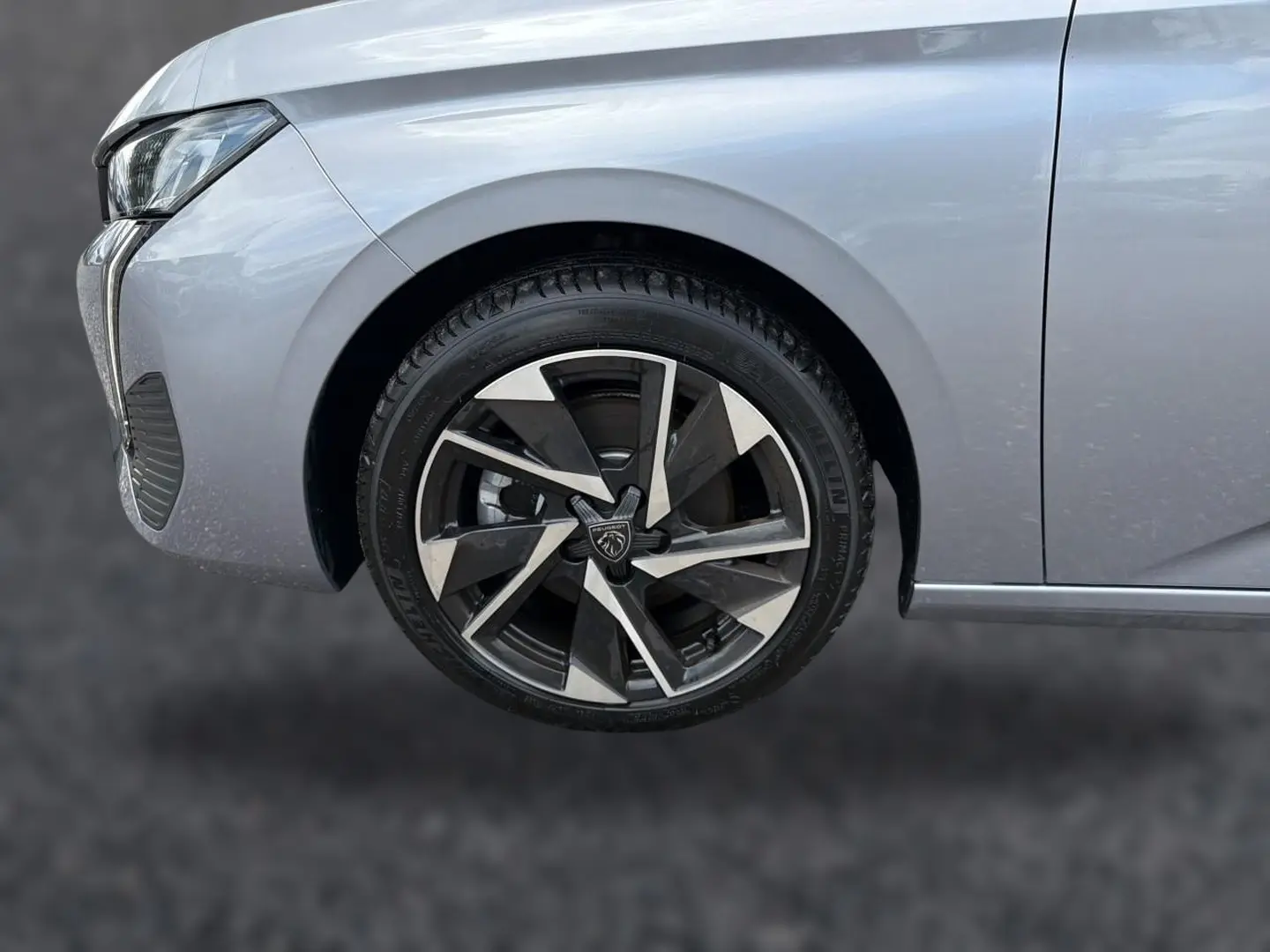 Gros plan sur la roue avant gauche et partie du pare-chocs gris d'une Peugeot 308 SW 2025 avec jante alu au design moderne.