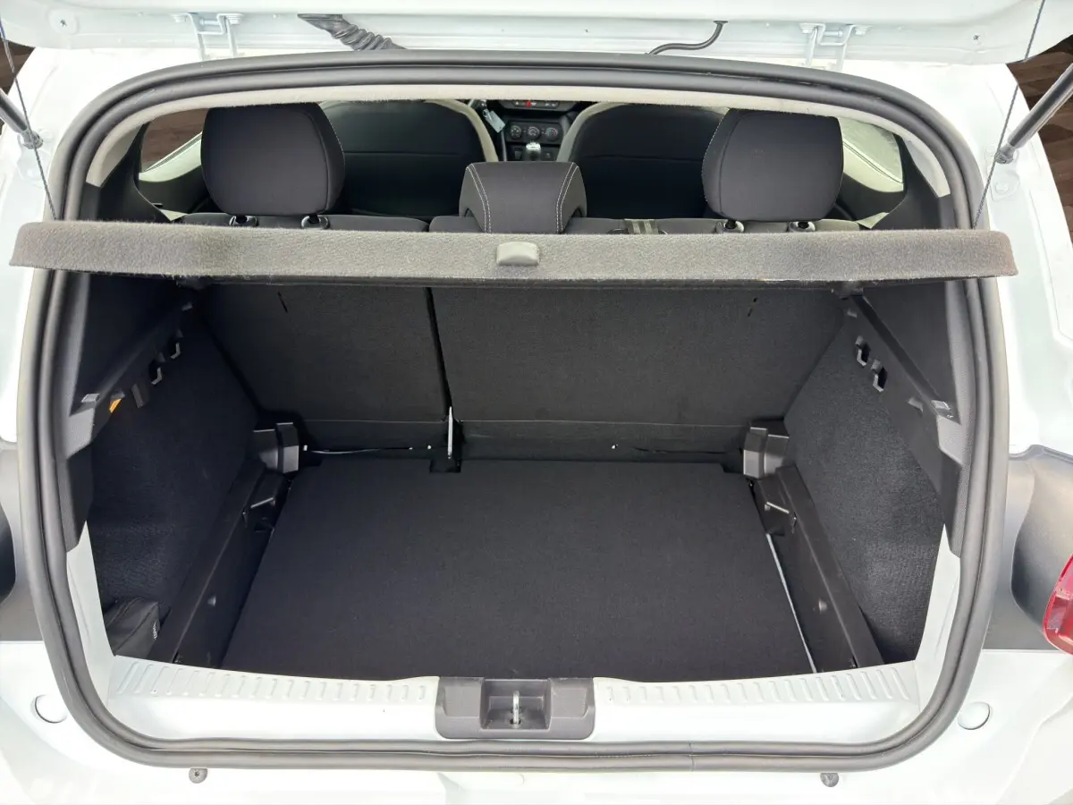 Vue arrière du coffre ouvert d'une Dacia Sandero Stepway blanche, montrant l'espace de chargement et la banquette arrière noire.