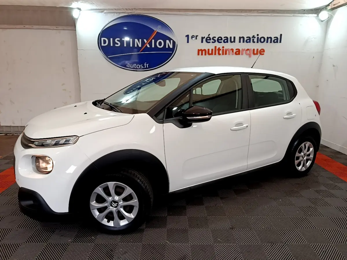 Citroën C3 blanche vue de profil côté gauche dans un showroom avec logo Distinxion en arrière-plan.
