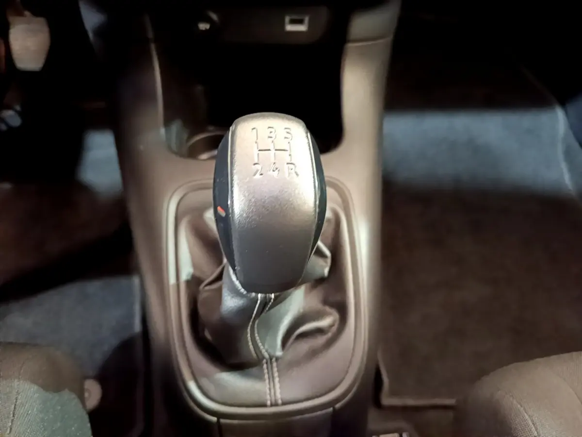 Le levier de vitesses manuel noir de la Citroën C3 blanche vu de dessus, entouré de l'habitacle sombre.