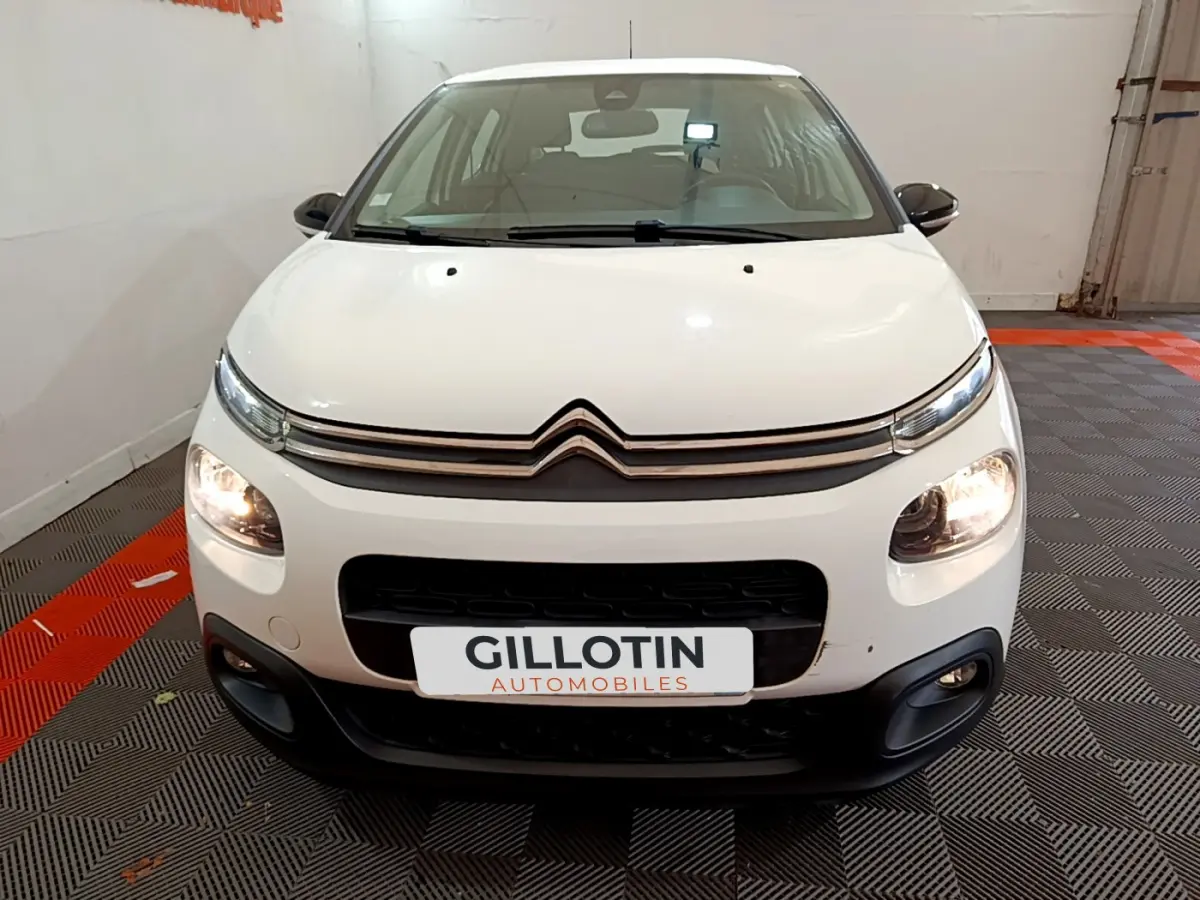 Vue frontale d'une Citroën C3 blanche 2019 avec phares allumés et calandre noire distinctive.