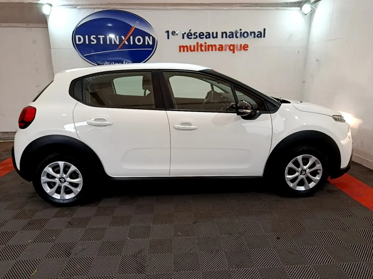 Profil côté gauche d'une Citroën C3 blanche 2019 avec jantes alliage et protections noires sur les passages de roue.