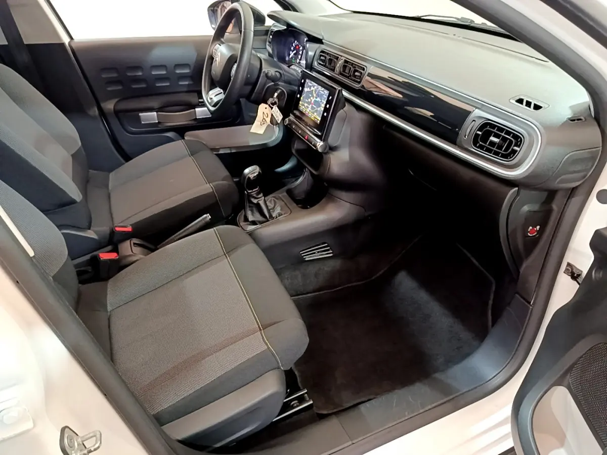 Intérieur avant droit d'une Citroën C3 blanche 2019, sièges gris, tableau de bord noir avec écran tactile central.