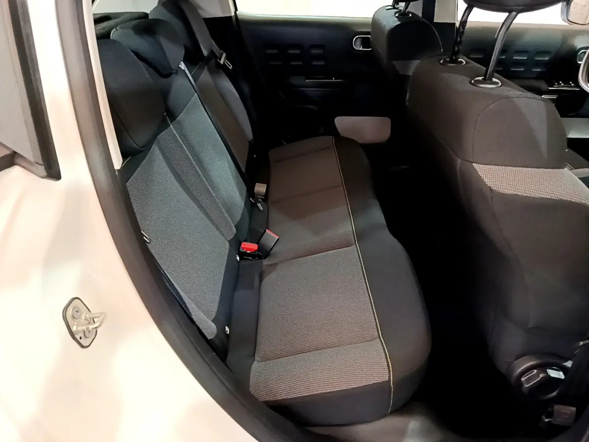 Vue intérieure côté gauche sur la banquette arrière grise d'une Citroën C3 blanche de 2019.
